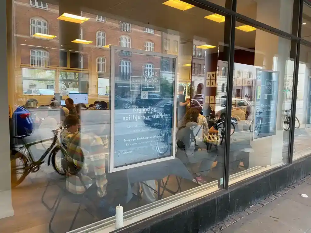 Børn og voksne samlet i Skakkens Hus Hjernens Motionscenter®, set gennem vinduet